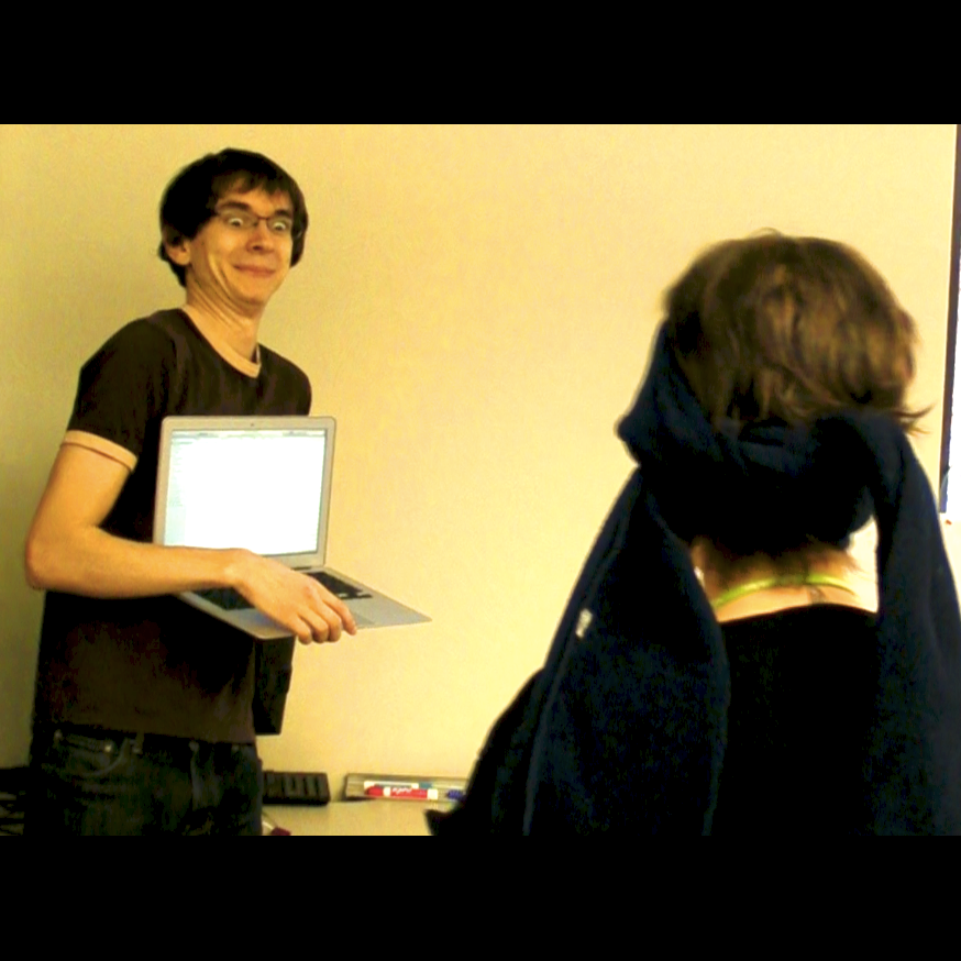 Joe Medwid holds a laptop and tries to avoid detection by a blindfolded tester