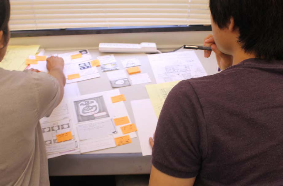 Asim Mittal and Christian Park put finishing touches on a paper prototype dotted with small orange Post-its